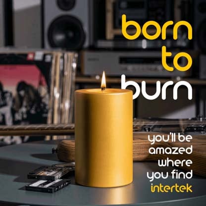 A lit candle sitting on a table next to various musical instruments